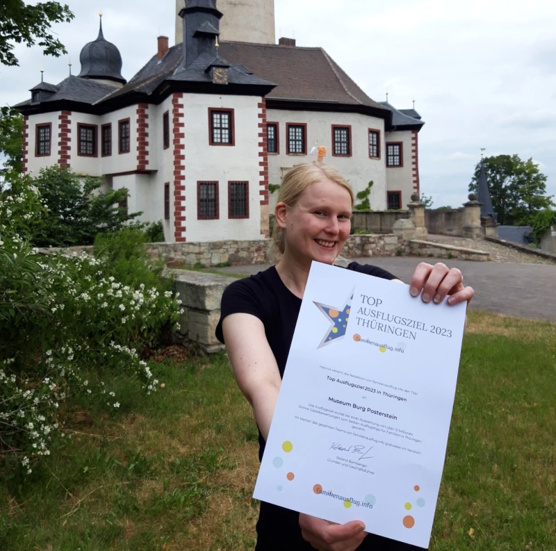 Burg Posterstein ausgezeichnet als TOP Ausflugsziel in Thüringen | Hier zeigt Museumsmitarbeiterin Franziska Huberty die Urkunde von Familienausflug.info. Franziska Huberty ist auch maßgeblich mitverantwortlich dafür, dass Burg Posterstein so familienfreundlich ist. Sie hat nicht nur die Ausstellung "Die Kinderburg" mit konzipiert, sondern führt derzeit fast täglich Schulklassen, Kitas und Kindergeburtstage auf unterhaltsame Art durch die Burg.