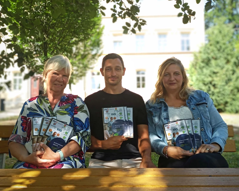 Volkshochschule startet mit Tag der offenen Tür ins Herbstsemester | VHS-Leiterin Gudrun Pfeiffer und ihre Mitarbeiter Kilian Kraus und Kristin Treichel (v.l.n.r.) präsentieren im „Grünen Klassenzimmer“ der Volkshochschule Altenburg das Programmheft für das Herbstsemester.