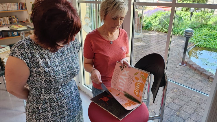 Auch ein Sachbuch ist unter den sechs möglichen Büchern. Heike Milke zeigt Hauptamtsleiterin Jacqueline Rödel das Buch im Detail. (Foto: Stadtverwaltung Schmölln)